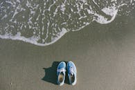 蓝色运动鞋铺在沙滩上，捕捉到海浪逼近前的宁静海滩时刻