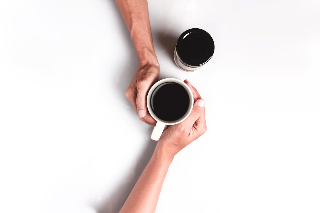 Two Person's Hand Holding White Mug Filled With Coffee