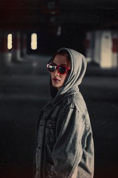 Portrait of a woman in a denim jacket and sunglasses, exuding urban style.