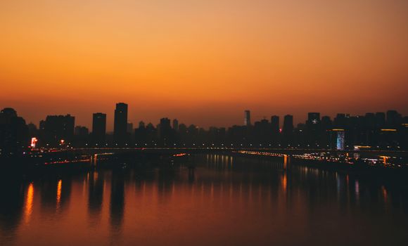 Stunning sunset over Chongqing skyline with river reflections creating a vibrant cityscape.