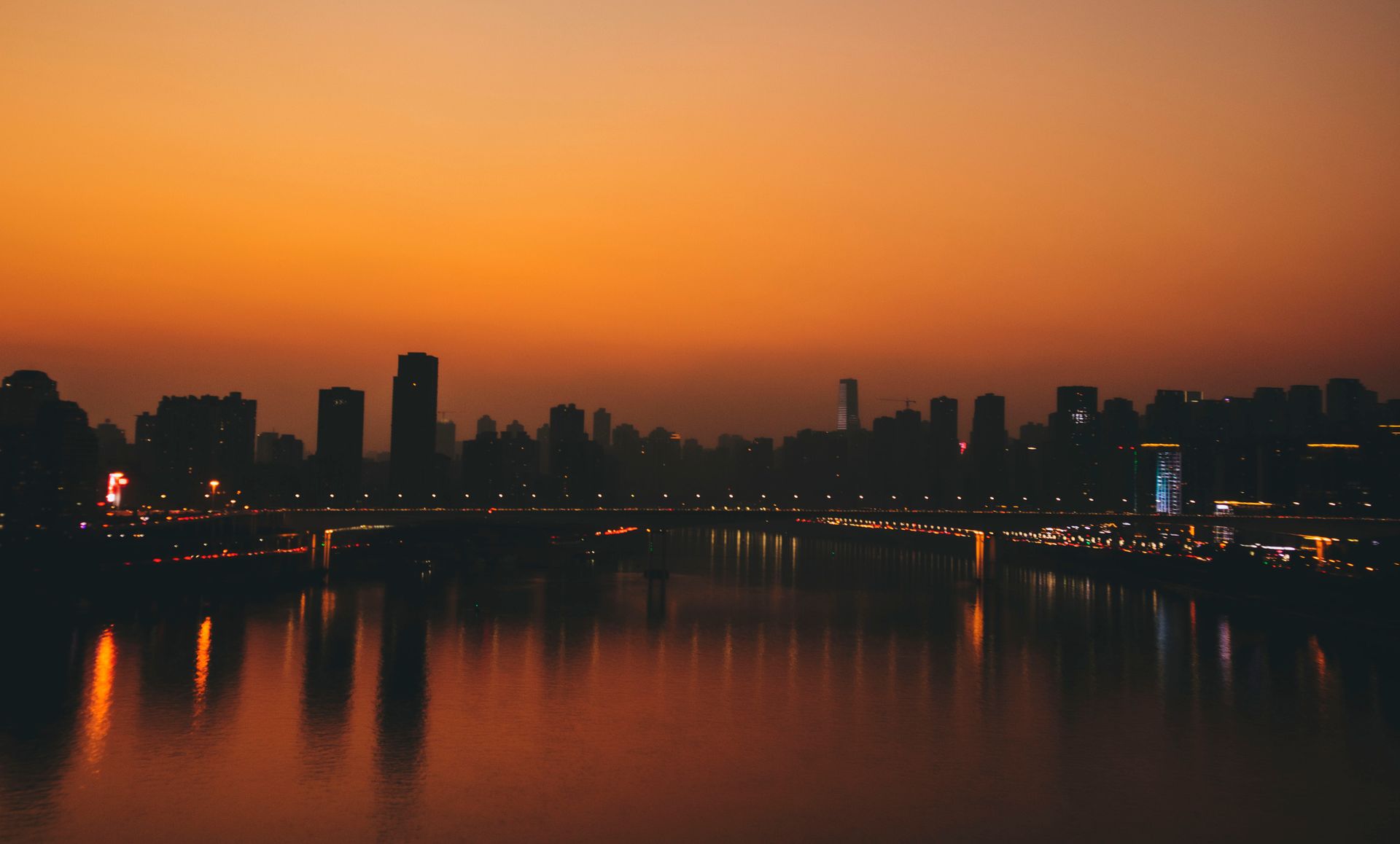 Stunning sunset over Chongqing skyline with river reflections creating a vibrant cityscape.