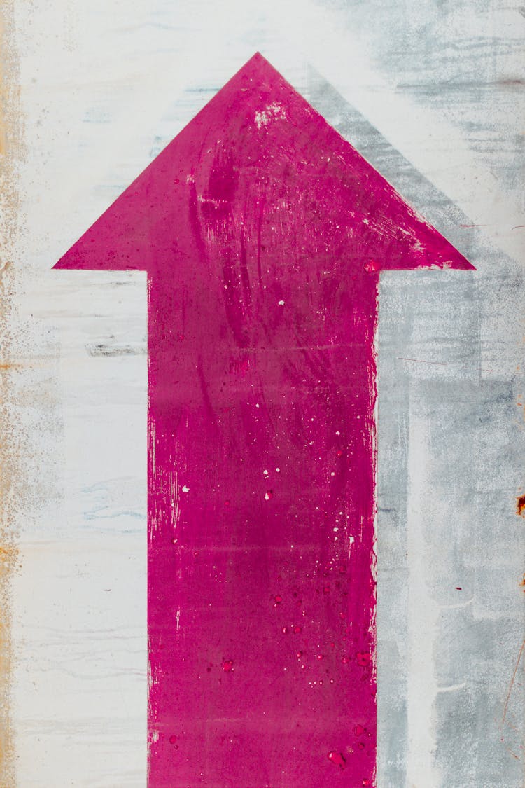 Painted Pink Up Arrow Sign On White Wall