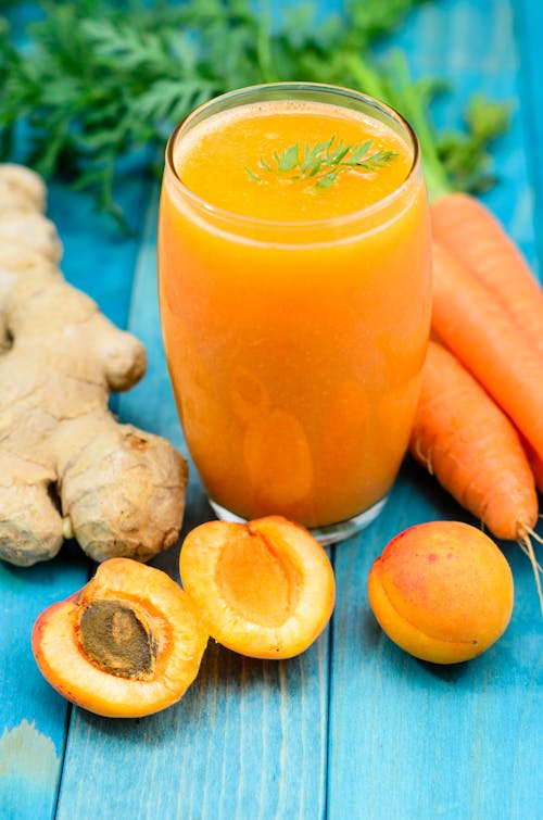 Glass of Apricot-Carrot Juice on Blue Wooden Table