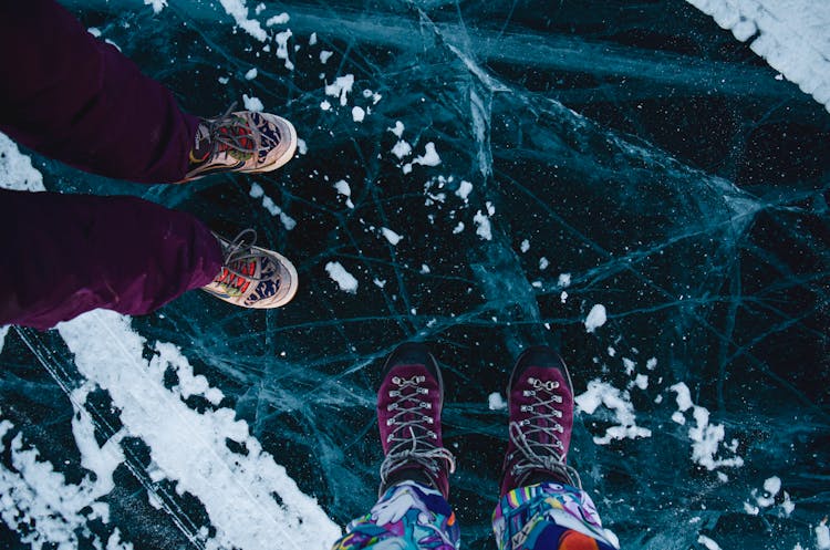 Feet Of People Ice Skating On Frozen Lake