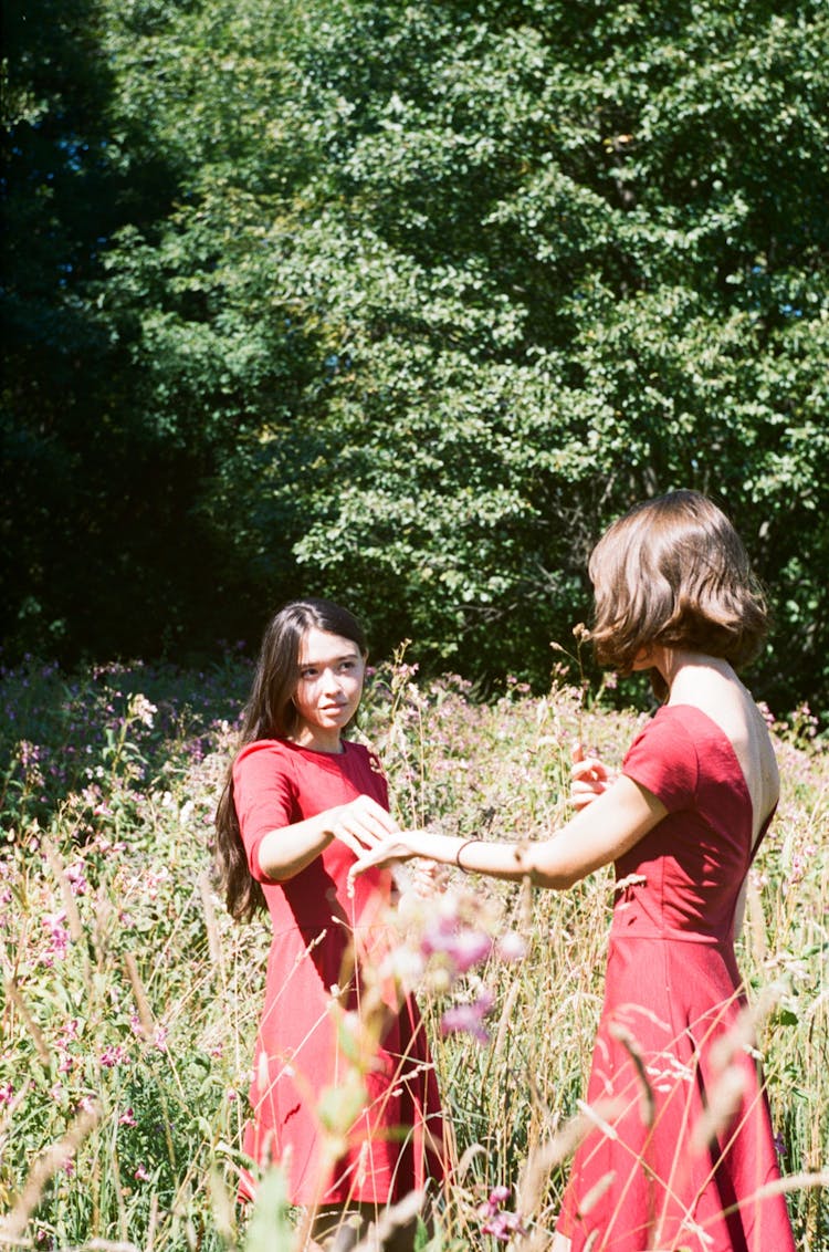 Girls In Red Dresses On Flower Field