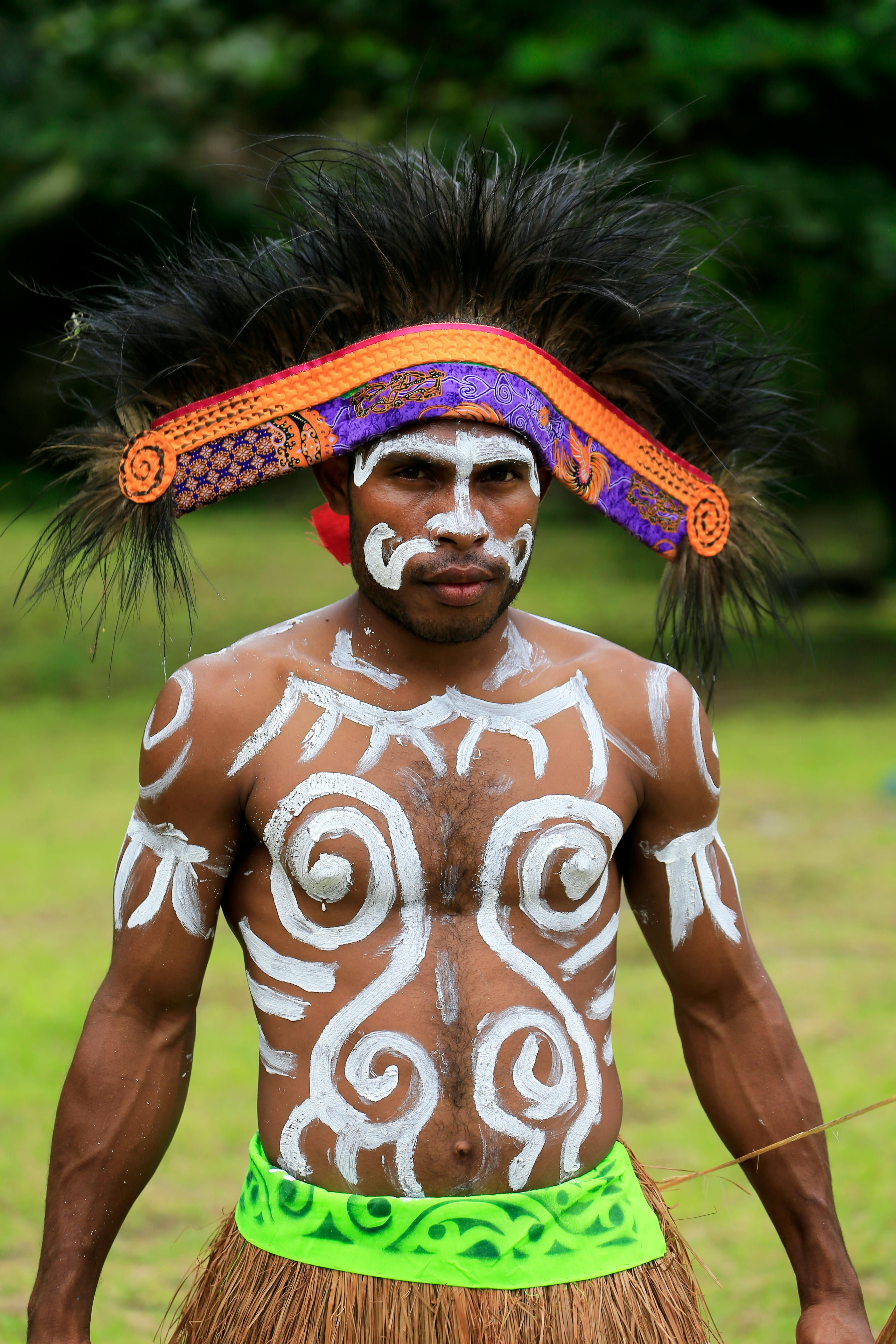 Portrait of a man with tribal body paint and traditional headwear in Papua, Indonesia.