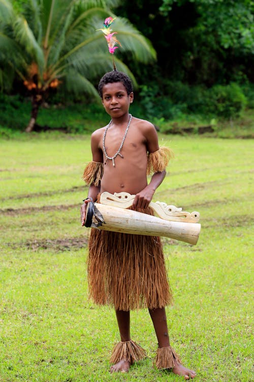 Shirtless Boy Wearing Straw Skirt Holding a Wooden Object
