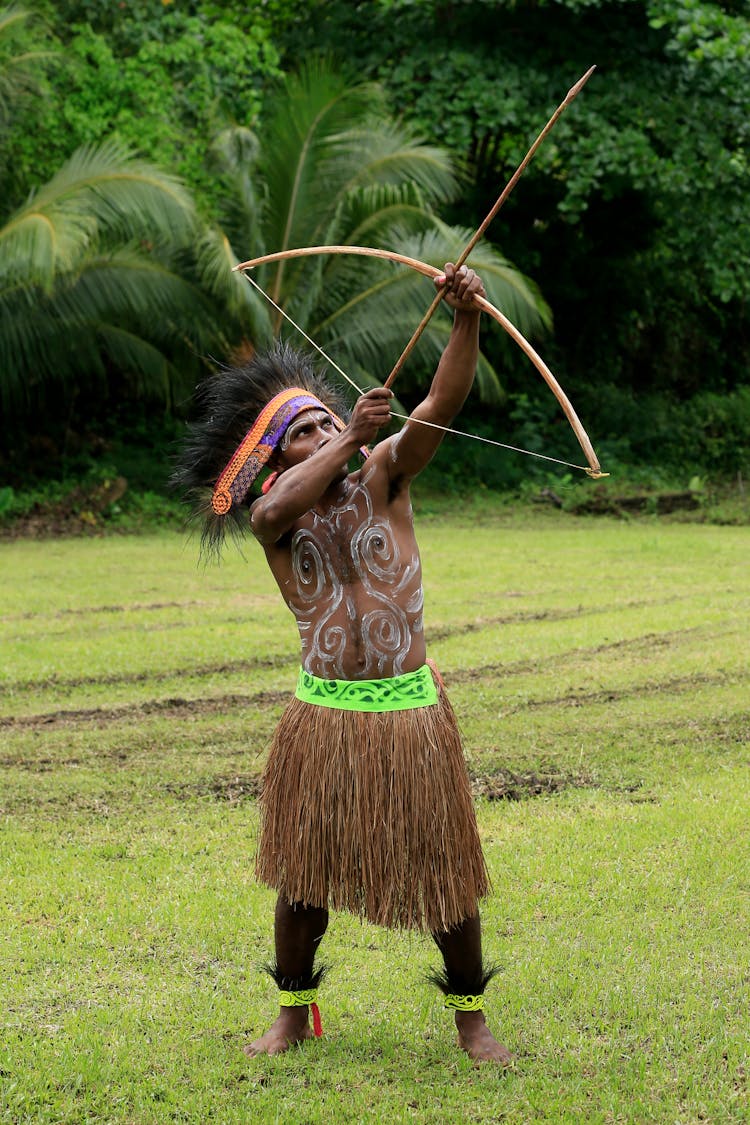 A Man In Straw Skirt Shooting An Arrow