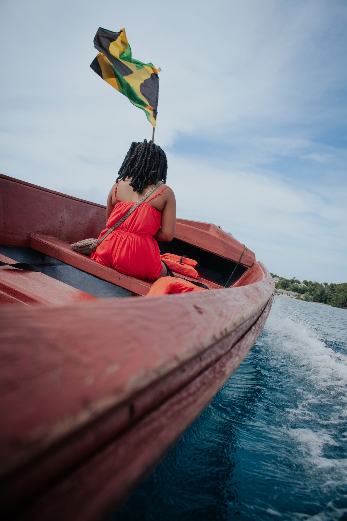 Traveler riding in a boat beneath the Jamaican flag
