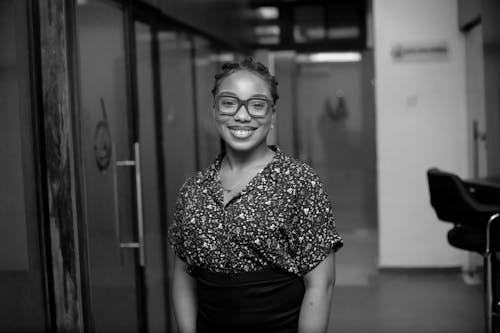 Grayscale Photo of a Woman Wearing Eyeglasses Smiling