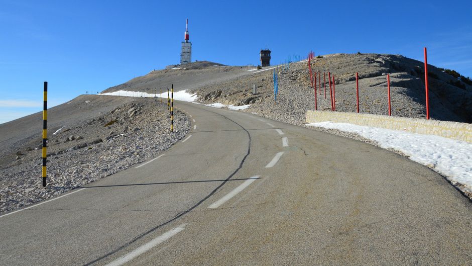 Scenic road ascending Mont Ventoux with iconic towers and clear sky.