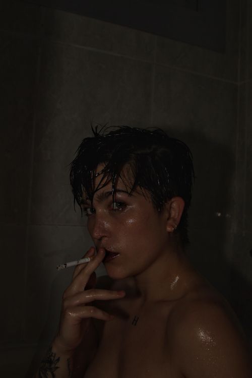 Free Artistic portrait of a woman indoors with wet hair and a cigarette creating a moody atmosphere. Stock Photo