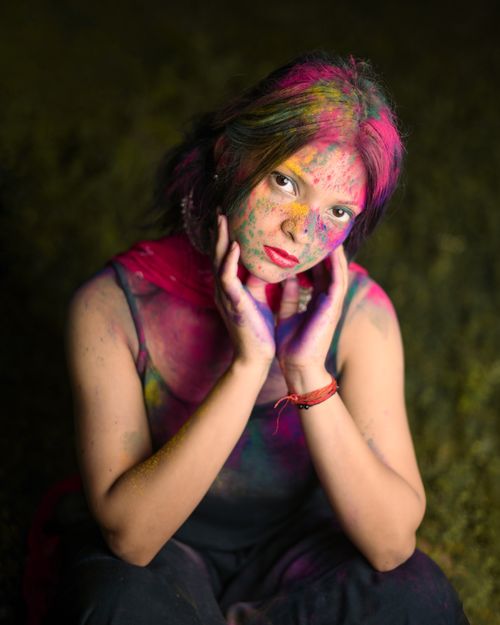 Free Vibrant portrait of a young woman with colorful powders on her face celebrating Holi. Stock Photo