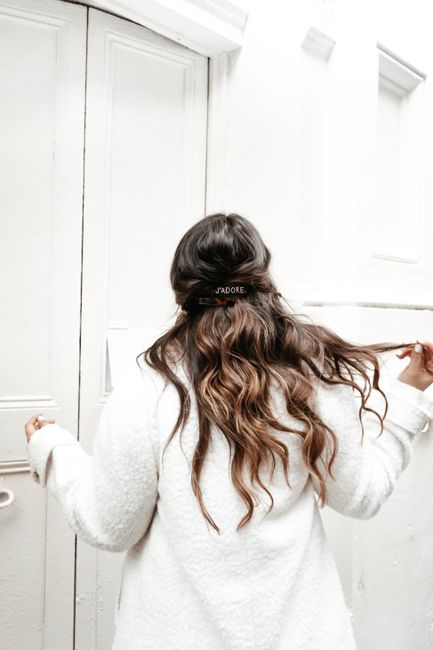 Back view of a woman wearing a white fur coat and holding her flowing hair.