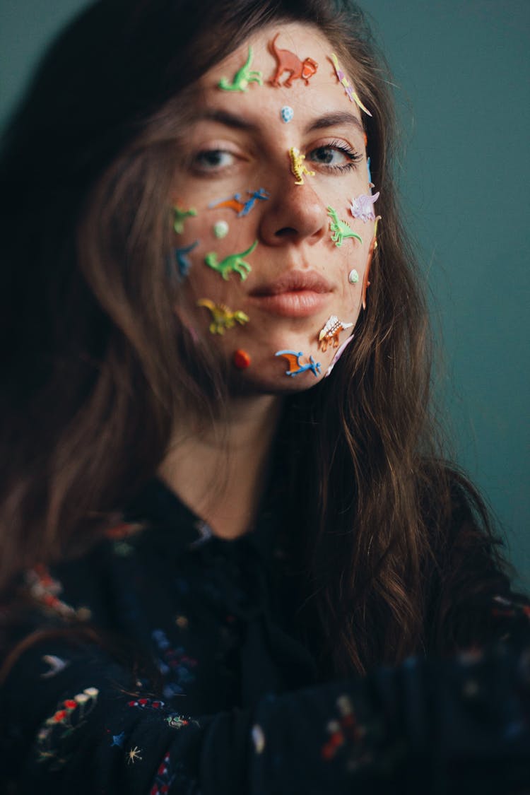 Young Woman With Colorful Dinosaur Stickers On Her Face 