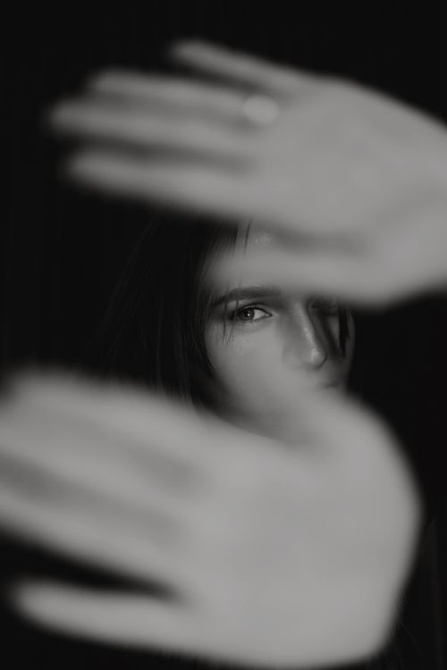 Free Creative portrait of woman with focus on eyes, framed by hands in black and white. Stock Photo