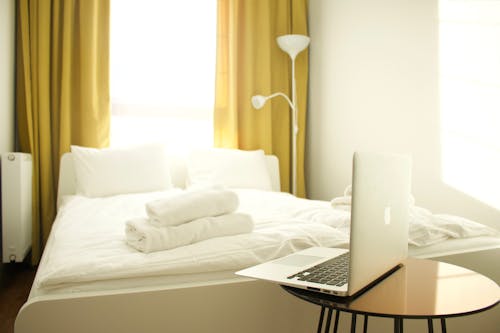 Ücretsiz Yatağın Yanında Kahverengi Ahşap Masa üzerinde Macbook Air Stok Fotoğraflar