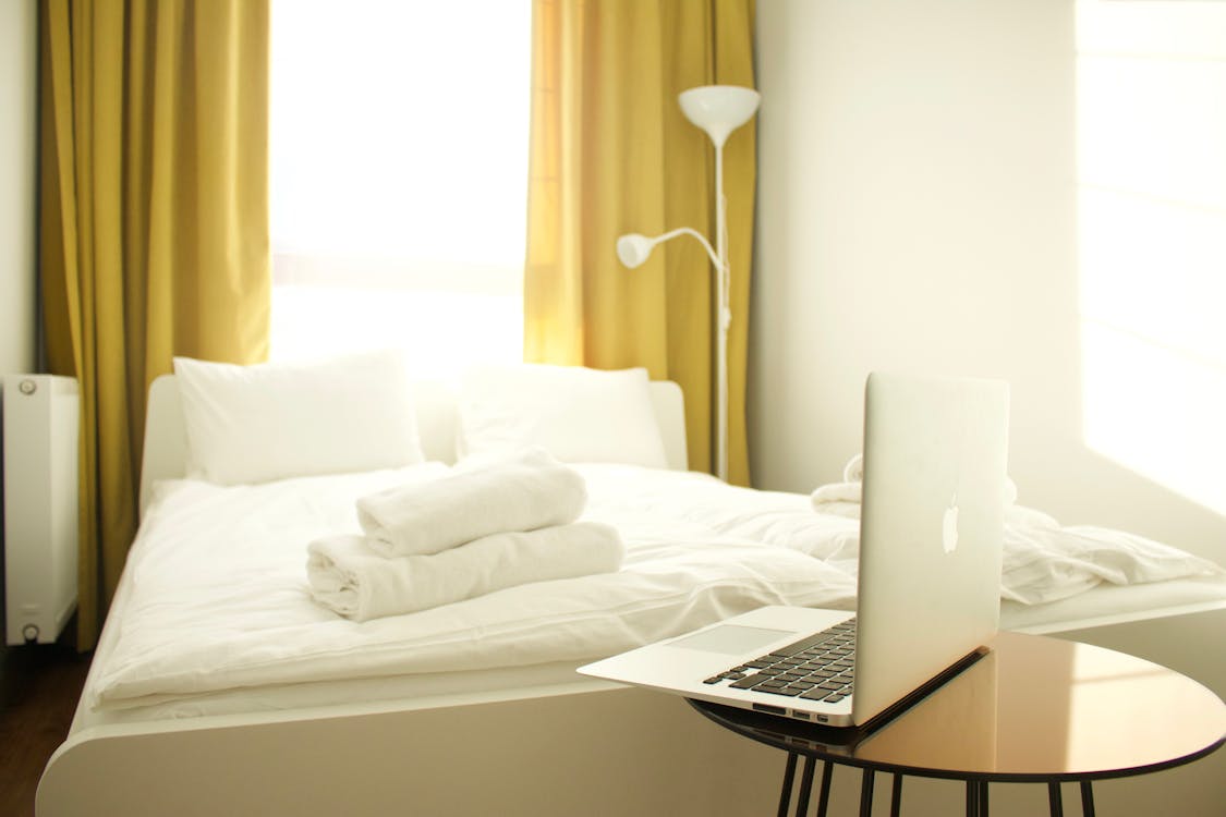 Free Macbook Air En Mesa De Madera Marrón Cerca De La Cama Stock Photo