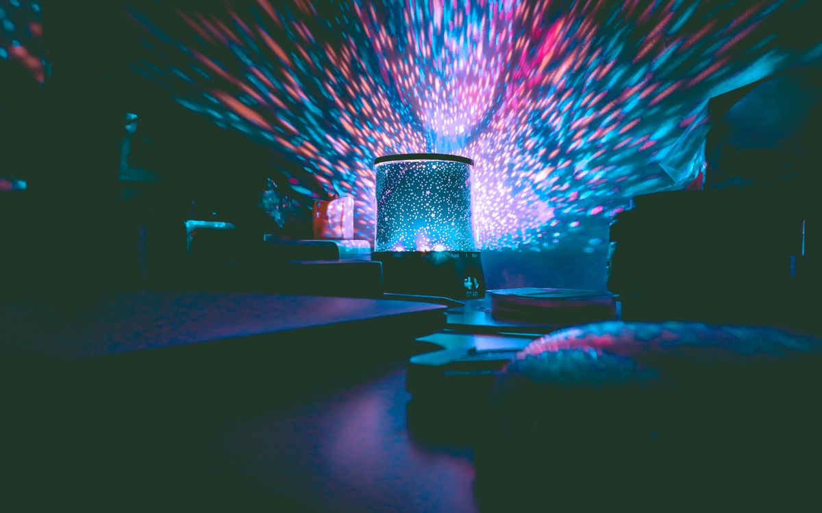 A colorful galaxy projector casting vibrant lights in a dark room. Perfect for setting a calm ambiance.
