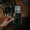 Hand Holding a Polaroid Camera with a Cat Photo