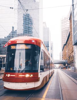 A modern streetcar travels through the bustling streets of Toronto, Canada.