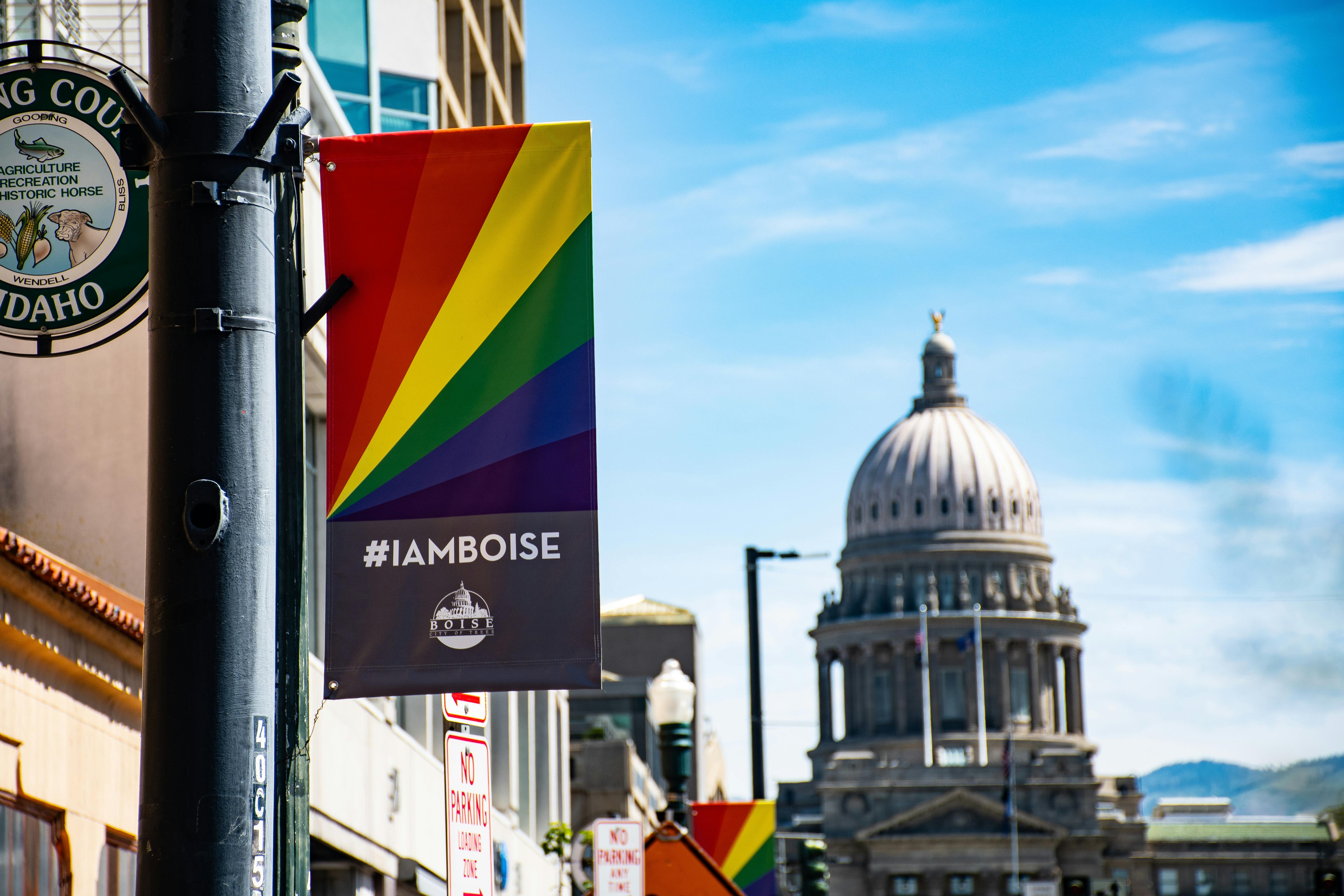 View of the Boise Capitol building with a rainbow pride banner in bright daylight.