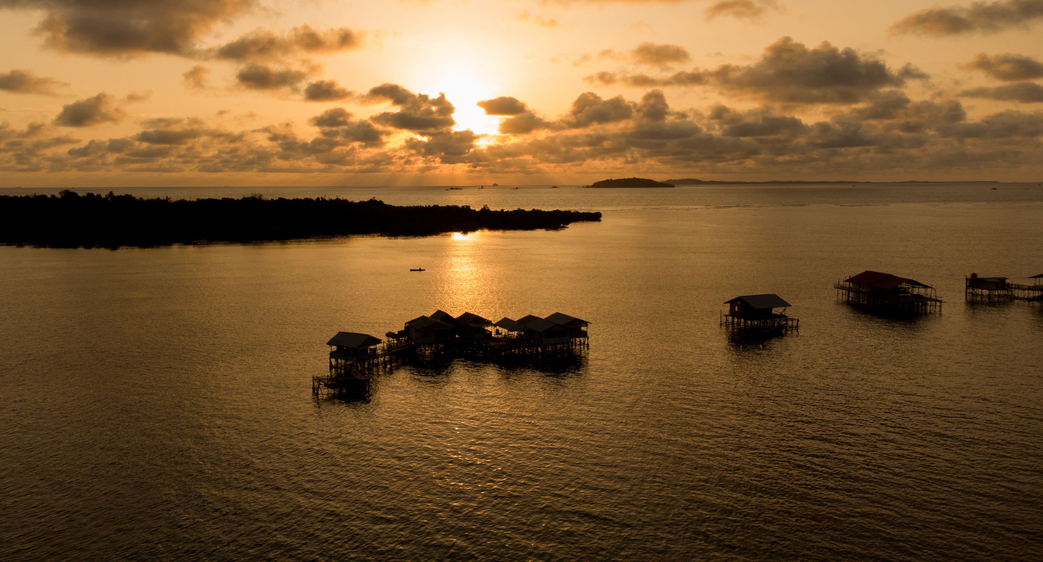 Aerial view of traditional stilt houses in Kepulauan Riau, Indonesia at sunset.