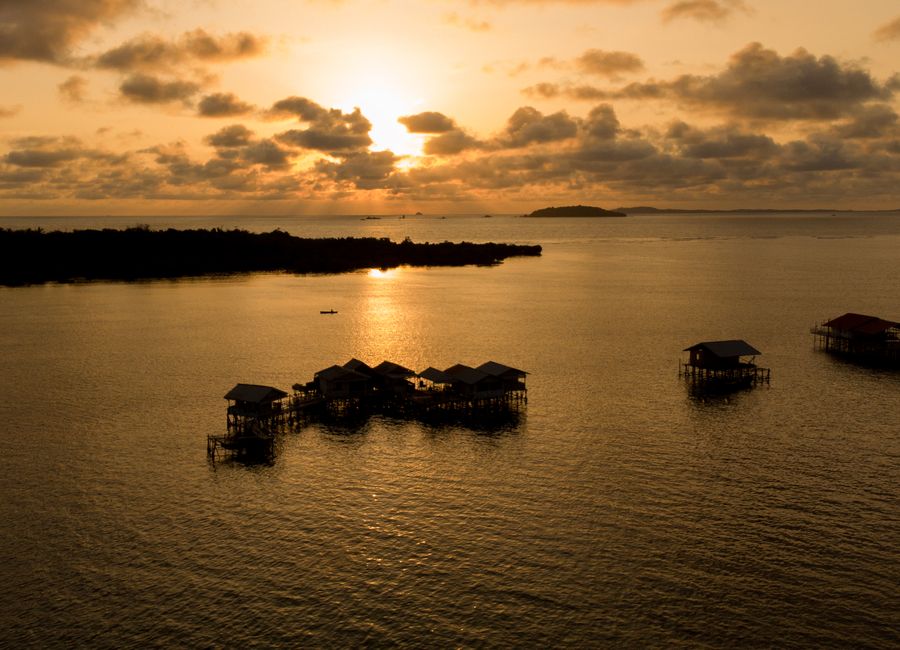 Aerial view of traditional stilt houses in Kepulauan Riau, Indonesia at sunset.