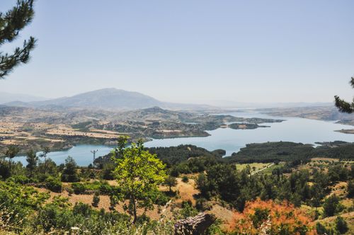 Free Breathtaking landscape featuring a lake, hills, and lush greenery under a clear sky. Stock Photo