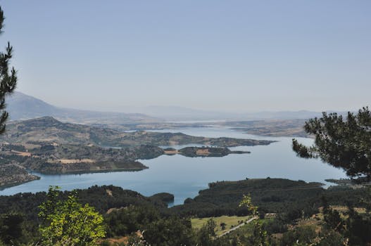 Breathtaking landscape of a scenic reservoir surrounded by hills and valleys under a clear blue sky.