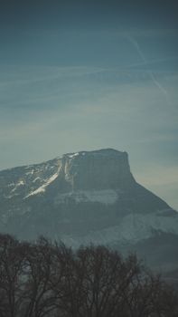 A tranquil winter view of a snow-capped mountain peak against a misty sky.