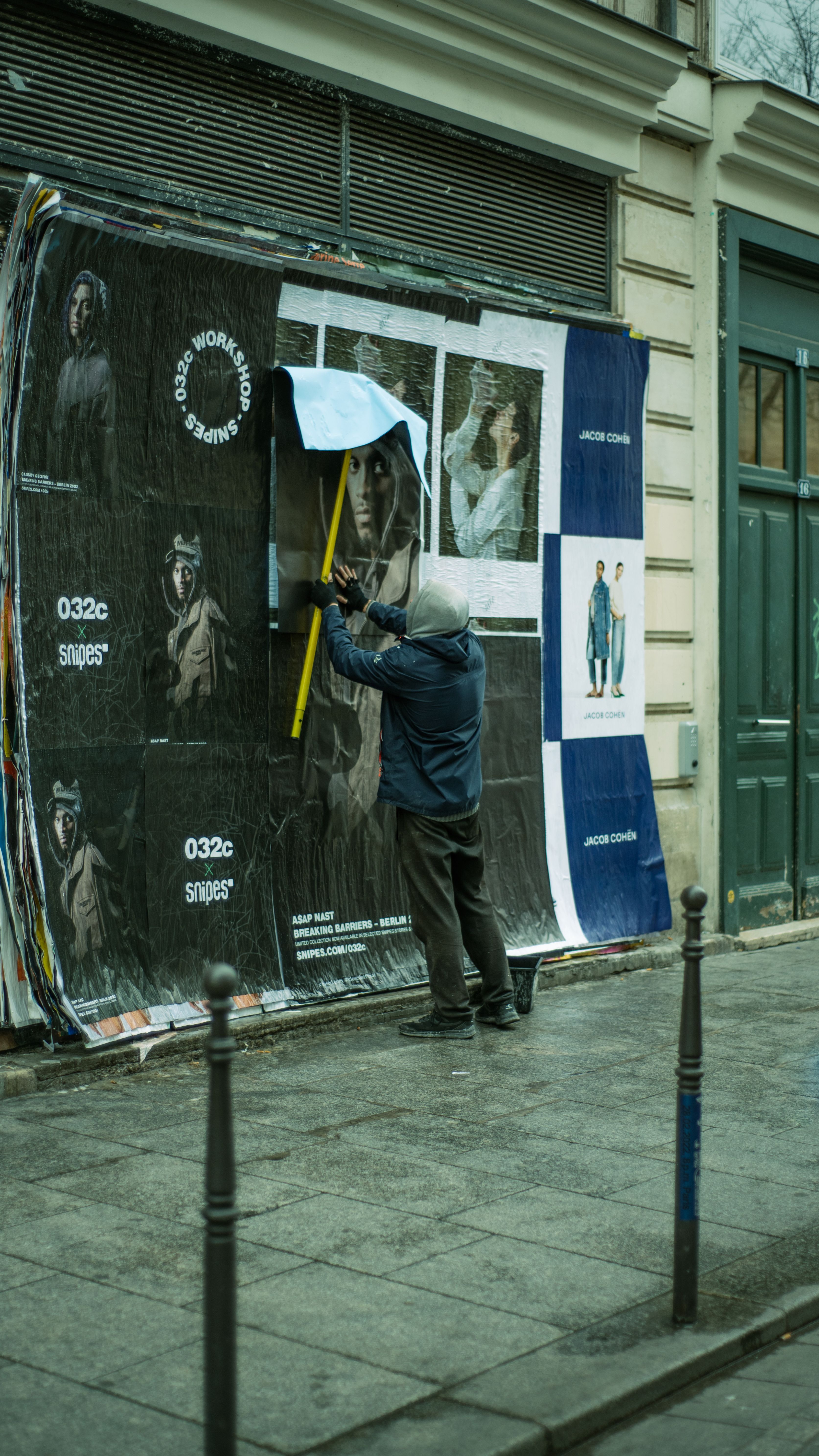 Man in Blue Jacket Posting Poster on Wall · Free Stock Photo