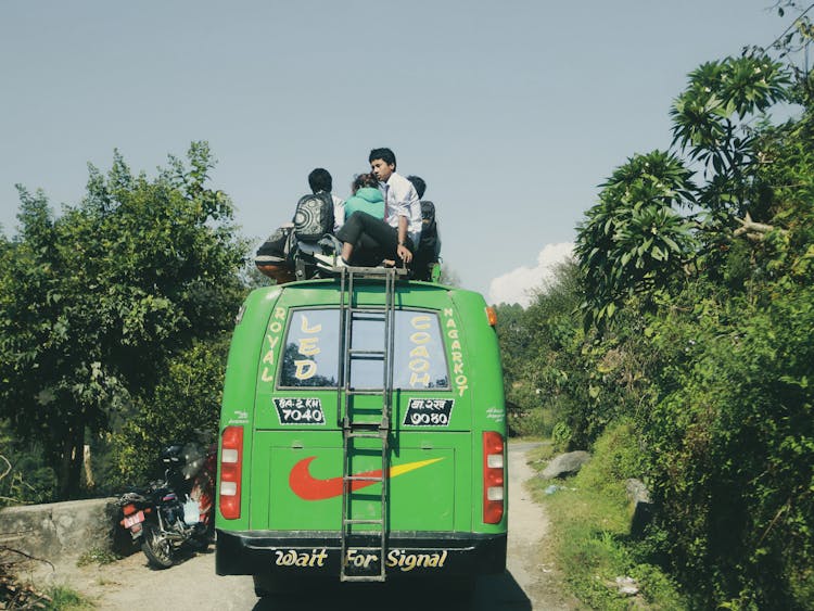 People Riding On Top Of A Green Bus