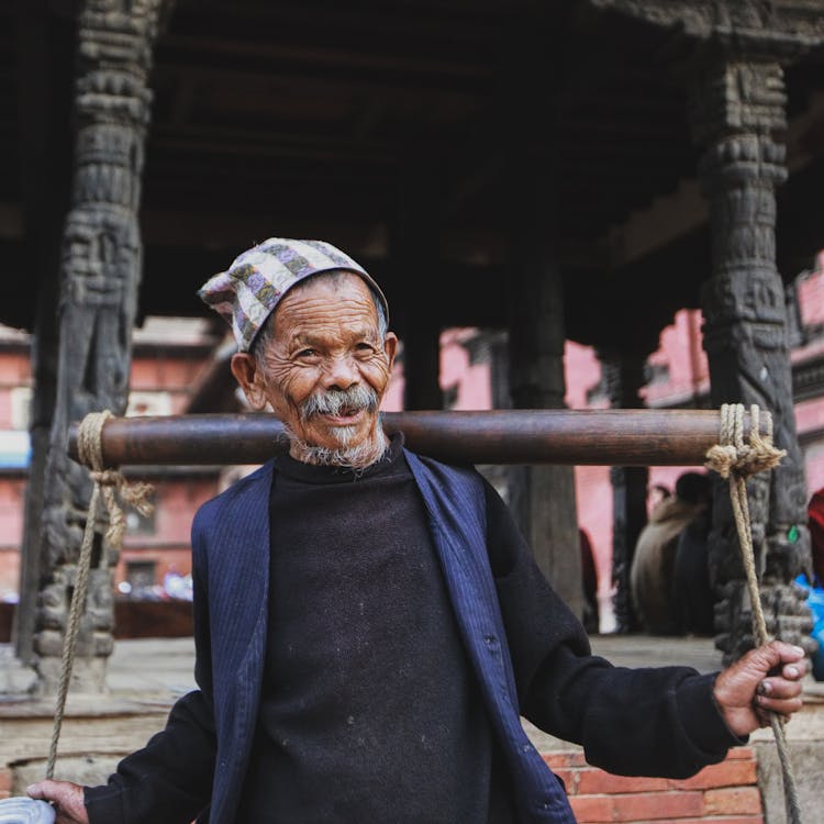 Old Man Carrying A Heavy Bar On His Back