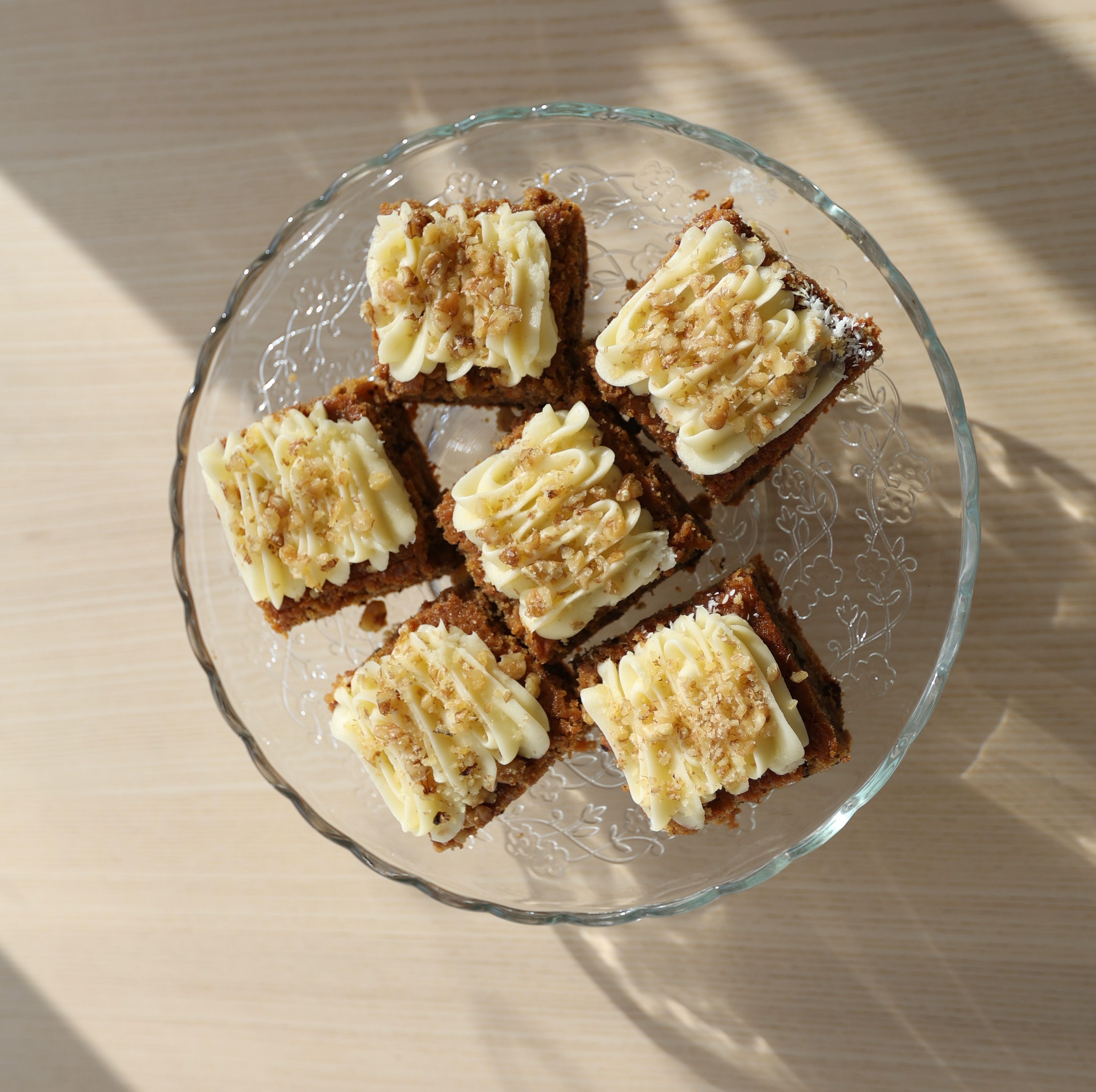 A pan of frosted pumpkin bars cut into squares, showing the moist orange crumb and swirled cream cheese frosting on top, dusted with a little cinnamon.