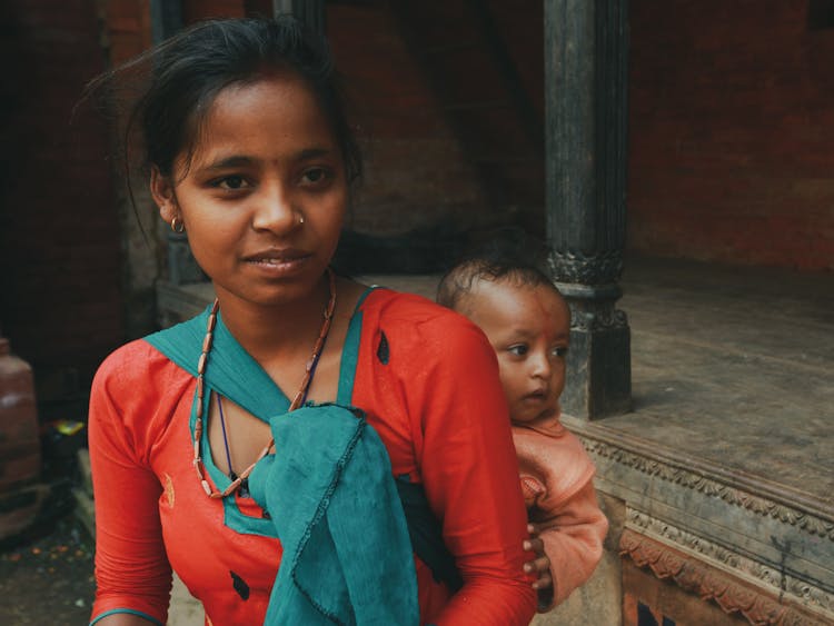 Portrait Of Young Woman Carrying Baby On Her Back