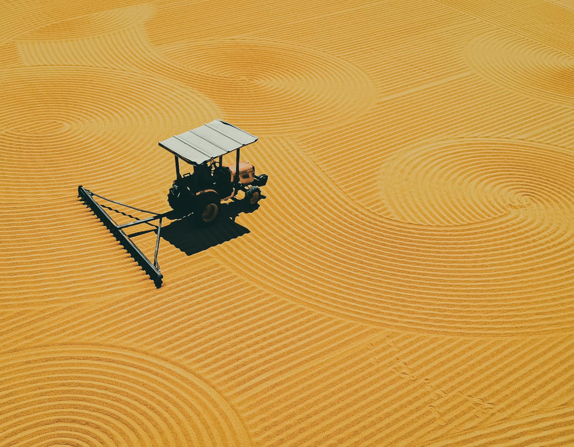 Aerial shot of a tractor creating spiral patterns on a golden field in Gaziantep, Turkey.