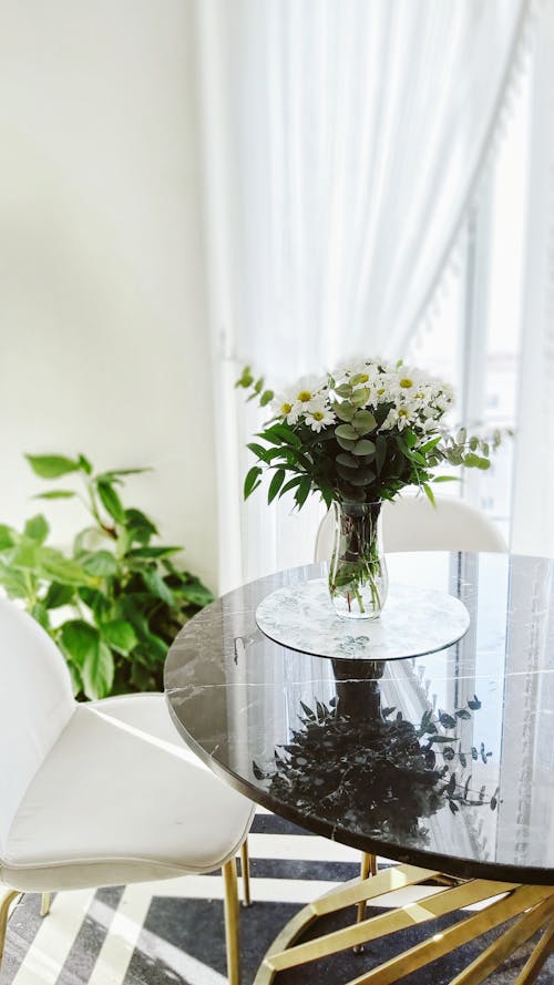 White Flowers in Clear Glass Vase on Round Marble Table