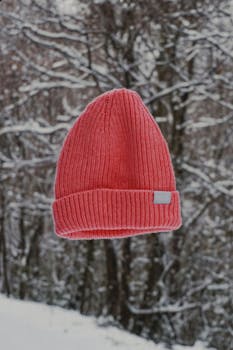 Cozy red knit winter hat floating in a snowy Turkish forest setting