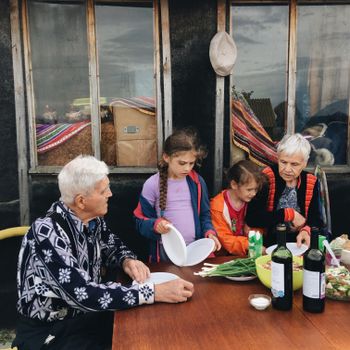 Elderly couple enjoying outdoor dinner with grandchildren, sharing moments and stories together.