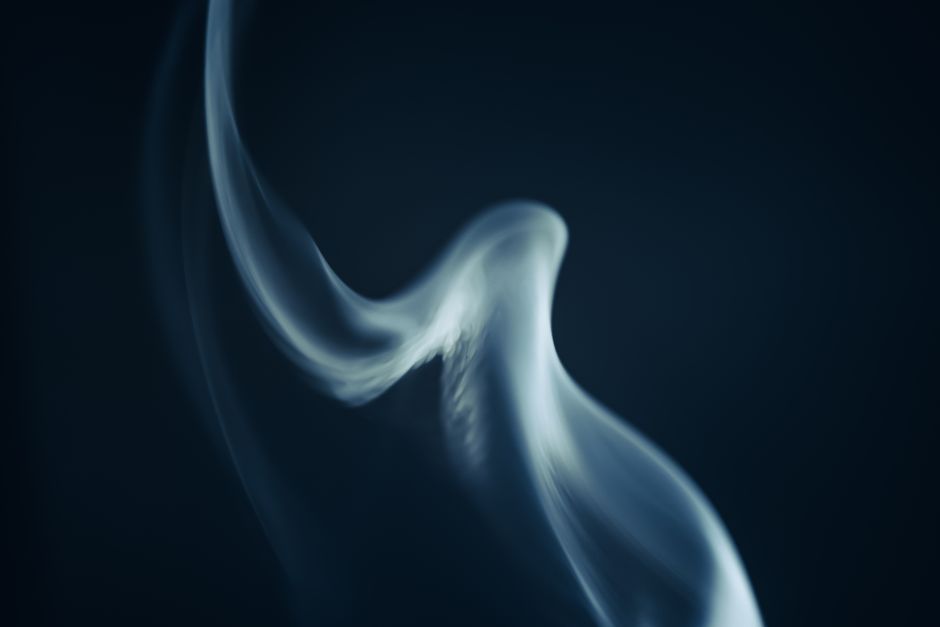 Mysterious swirling smoke gracefully captured against a dark background, creating a mesmerizing abstract effect.