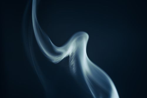 Free Mysterious swirling smoke gracefully captured against a dark background, creating a mesmerizing abstract effect. Stock Photo