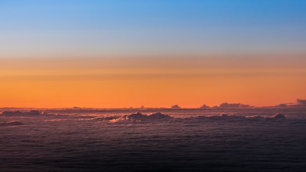 A beautiful sunset sky with vibrant colors above a sea of clouds, creating a serene atmosphere.