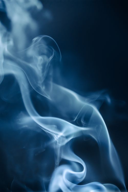 Free Ethereal blue smoke swirls gracefully against a dark backdrop, creating a smooth and mysterious atmosphere. Stock Photo