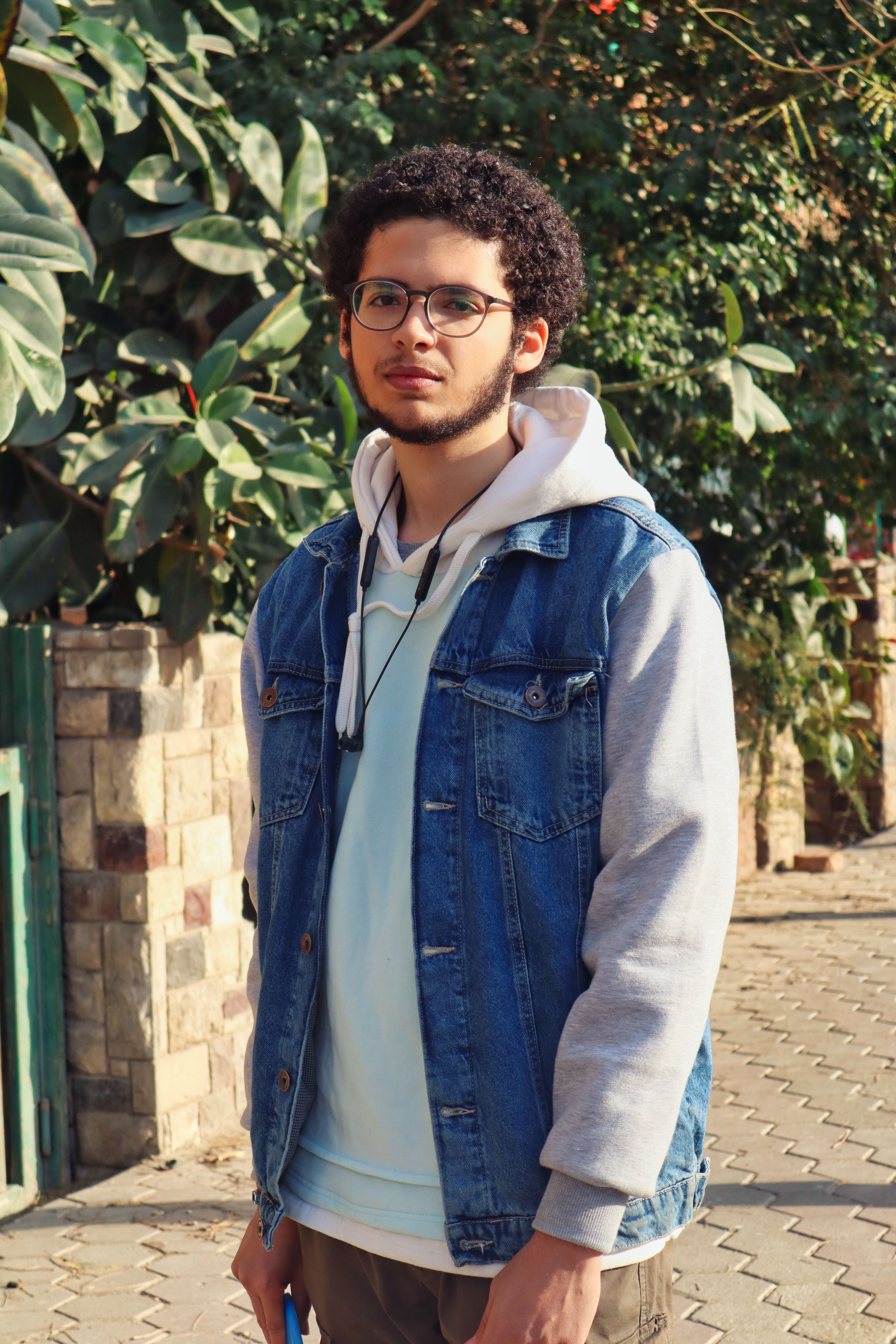 Portrait of a young man with curly hair and eyeglasses outdoors in Cairo.
