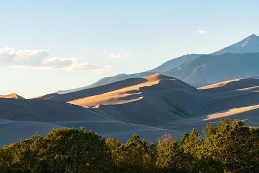 Sweeping view of sand dunes against mountains at sunset in Colorado's national park.