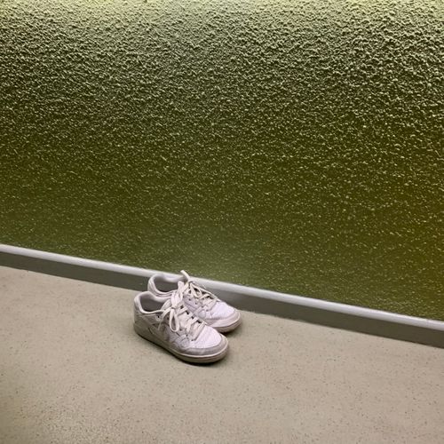 White canvas sneakers against an olive wall — photo by Clarisse Vidal on Pexels
