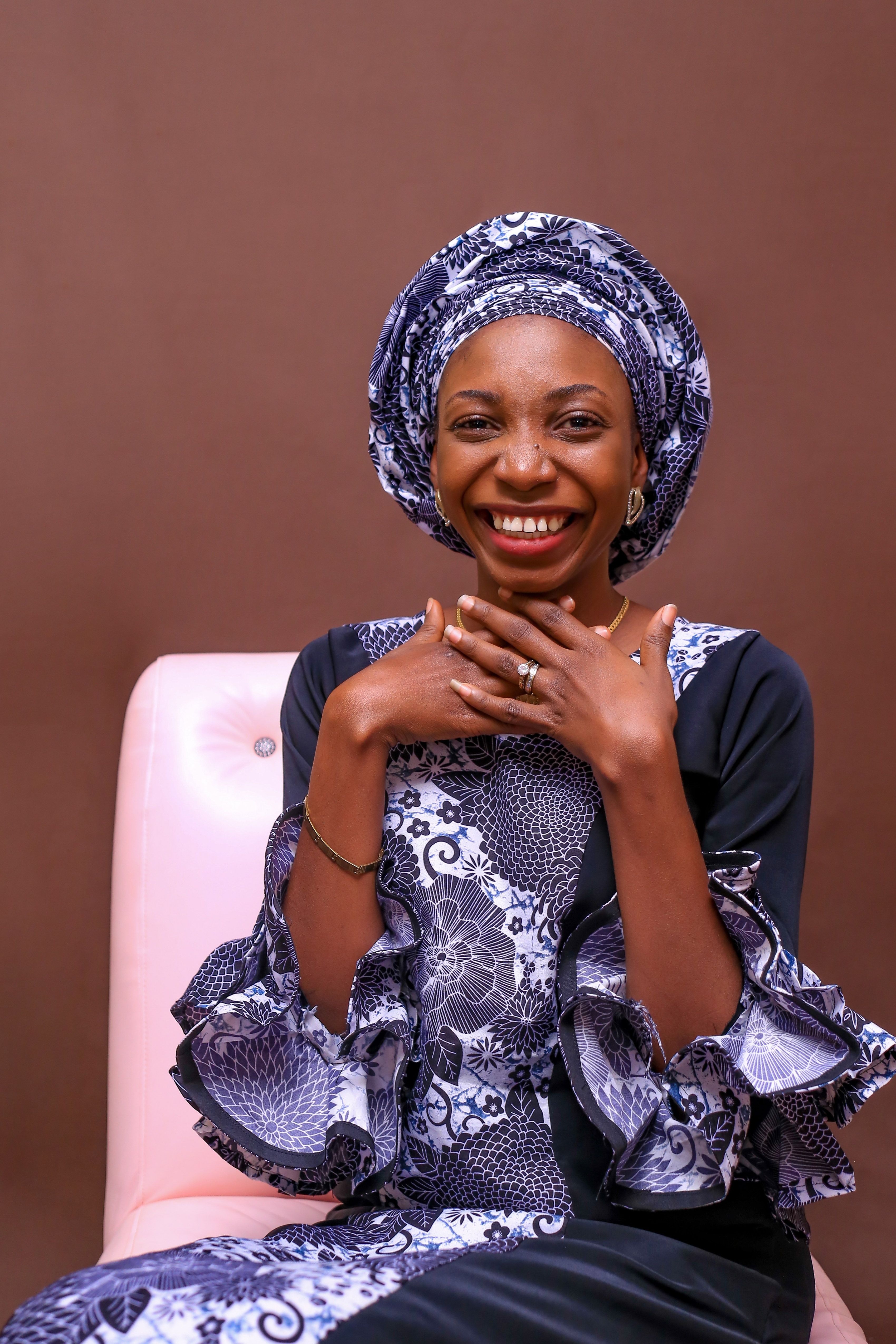 A joyful portrait of a woman in African attire with intricate patterns and a vibrant smile.