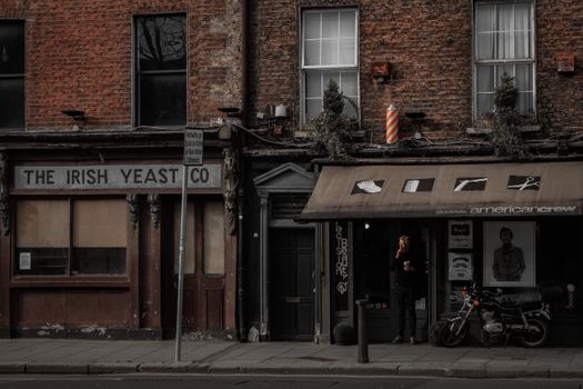 Urban street scene featuring a brick facade with a vintage shop and barber pole in a city setting.
