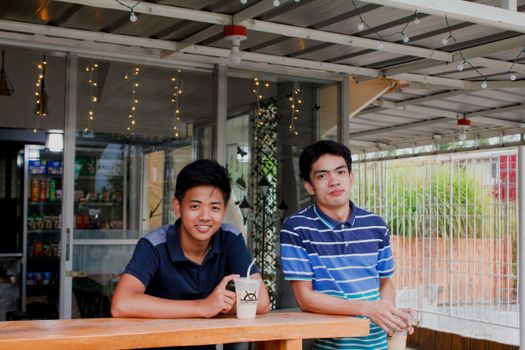 Two young adults enjoying milk tea at an outdoor cafe setting, capturing a casual moment.
